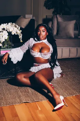 Busty black girl sitting on the floor on a rug