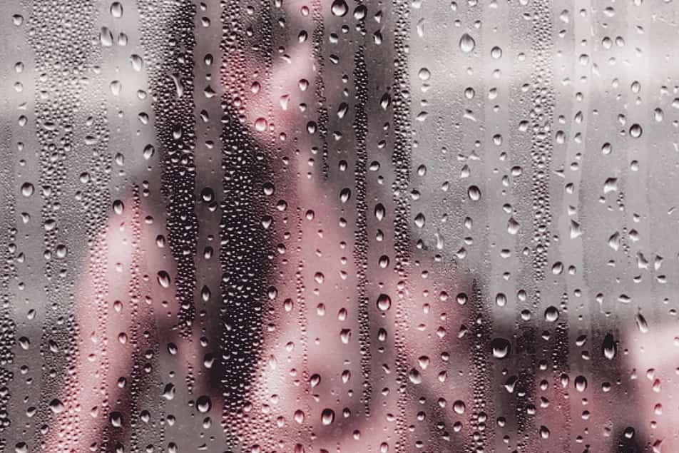 Naked girl taking a shower behind a misty window