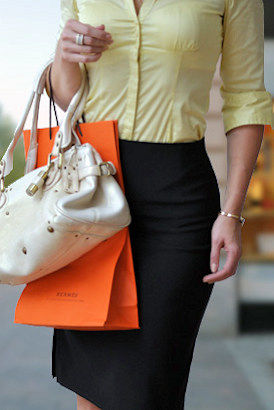 Girl about town in a tight yellow shirt holding shopping bags